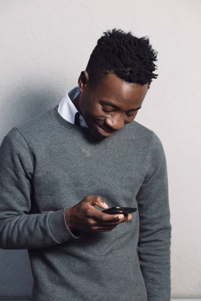 Αφρικανική αμερικανική άνθρωπος που χρησιμοποιούν κινητό τηλέφωνο κοντά σε τοίχο γκρι — Φωτογραφία Αρχείου