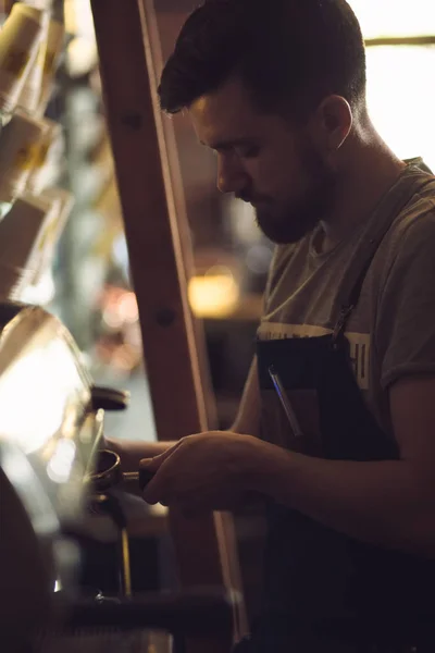 Mladý muž barista připravuje nápoj v kávovar — Stock fotografie