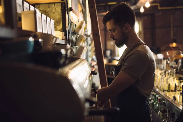 Mladý muž barista připravuje nápoj v kávovar — Stock fotografie