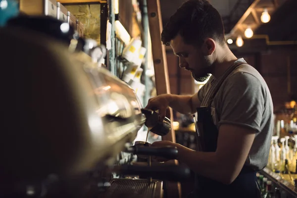 Mladý muž barista připravuje nápoj v kávovar — Stock fotografie