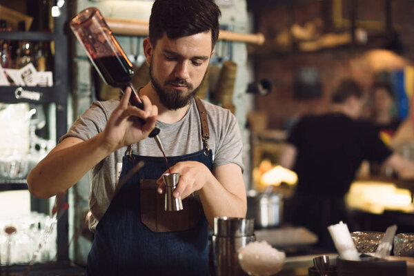 Young male bartender preparing an alcohol cocktail