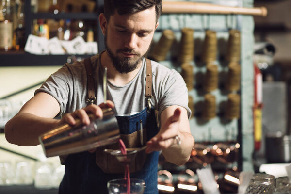 Young male bartender preparing an alcohol cocktail