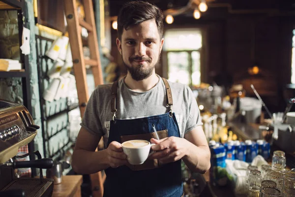 Barman houden een kopje cappuccino in een bar — Stockfoto