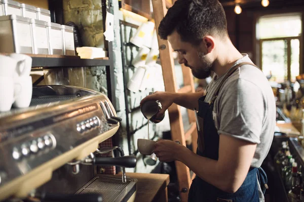 Joven barista masculino preparando bebida en la máquina de café — Foto de Stock