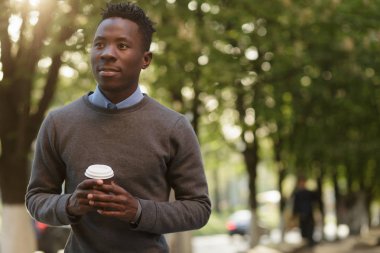 Afrika kökenli Amerikalı adam güneşli akşam şehirde çay içme