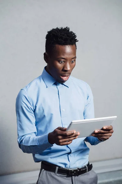 Afrikaner schaut verlegen auf Bildschirm des Tablets — Stockfoto