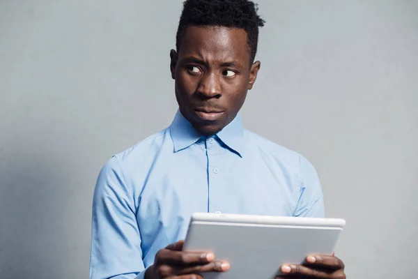 Afrikaner schaut verlegen auf Bildschirm des Tablet-PCs — Stockfoto