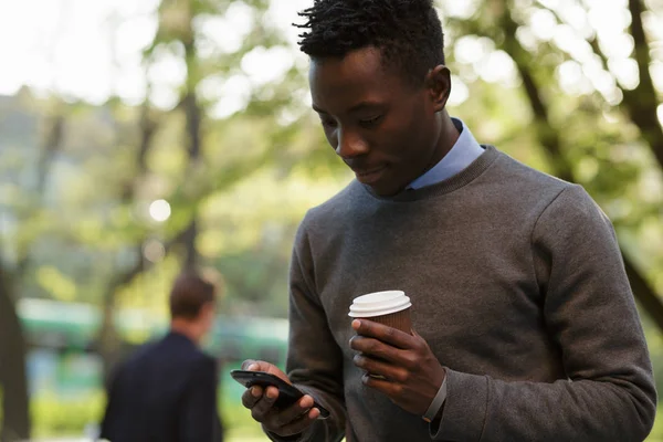 African american man walking and typing text in smartphone