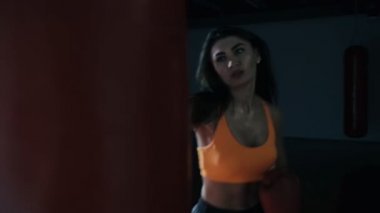 Genç kadın boks kum torbası karanlık bir salonda