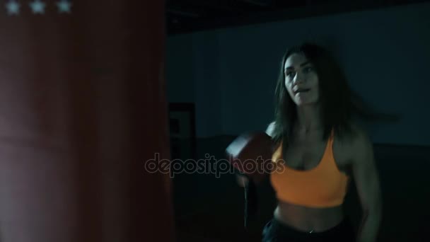 Genç kadın boks kum torbası karanlık bir salonda — Stok video