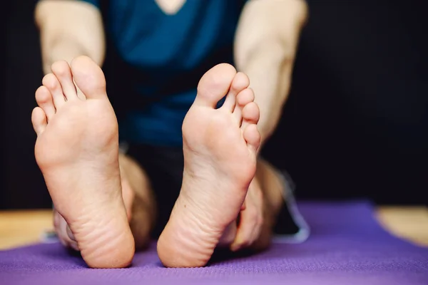 Hombre estirando sus piernas en la alfombra del piso —  Fotos de Stock