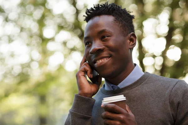 African american man talking by phone in sunny evening city