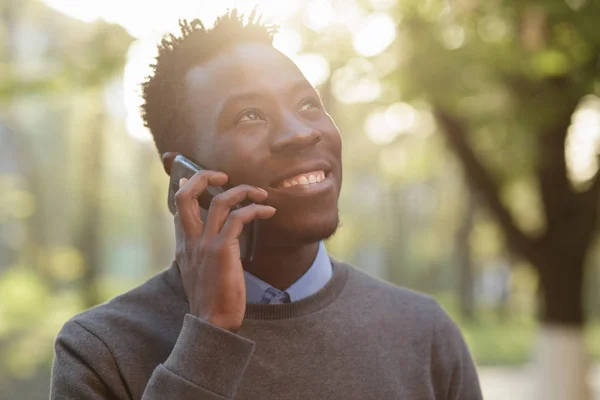 African american man talking by phone in sunny evening city