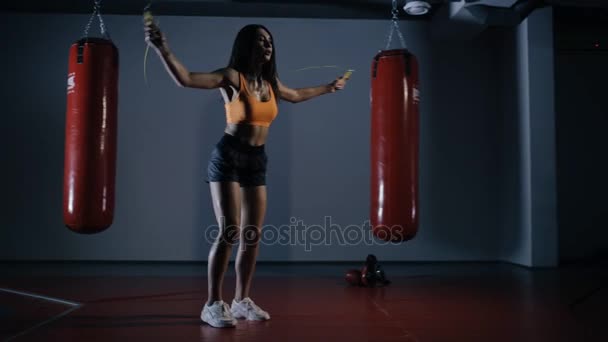 Mulher jovem boxeador pulando em uma corda pulando em um salão escuro — Vídeo de Stock