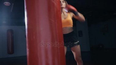 Genç kadın boks kum torbası karanlık bir salonda