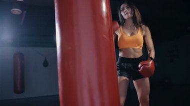 Genç kadın boks kum torbası karanlık bir salonda