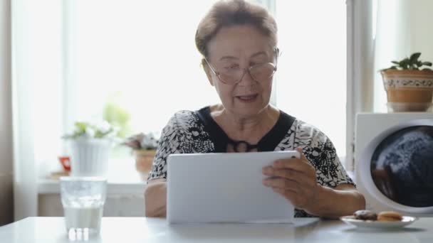 Mulher idosa moderna usando tablet PC em sua cozinha — Vídeo de Stock