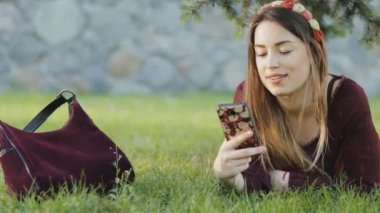 Bir çim üzerinde yalan ve smartphone kullanarak güzel kadın