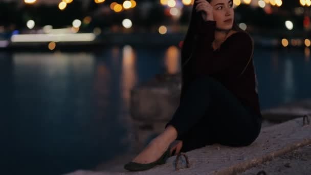 Wanita cantik duduk di jembatan di malam hari dan bersantai — Stok Video