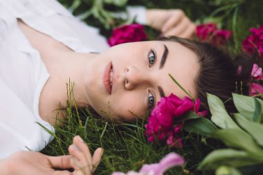 Kadın çiçek peonies ile çim üzerinde yalan