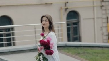 Buket çiçek ile şehirde yürüyen kadın