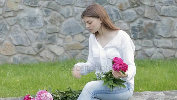 Woman makes peonies bouquet sitting in park — Stock Video