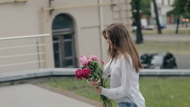 Mujer caminando en la ciudad con flores de peonías ramo — Vídeos de Stock