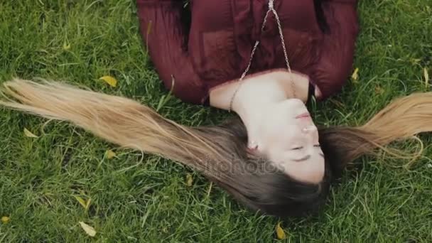 Красива жінка лежить на траві і розслабляється в літній день — стокове відео