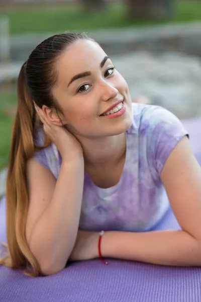 Mujer en una alfombra deportiva tumbado relajante al aire libre —  Fotos de Stock