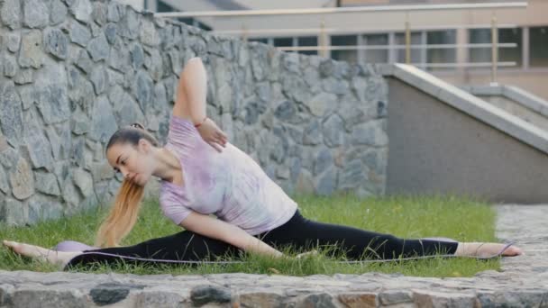 Woman practicing yoga exercise in a city lawn — Stock Video