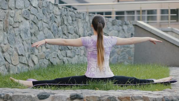 Sportliche Frau praktiziert Yoga auf dem Rasen der Stadt — Stockvideo