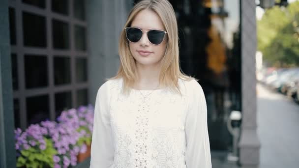 Mujer bonita caminando con gafas de sol en la ciudad, cámara lenta — Vídeo de stock