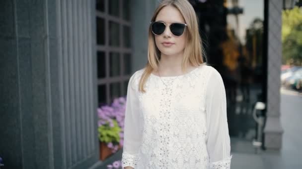 Pretty woman walking with sunglasses in city, slow motion — Stock Video