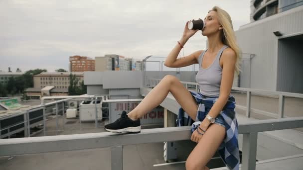 Mujer tomando café en una azotea de estacionamiento de la ciudad — Vídeos de Stock