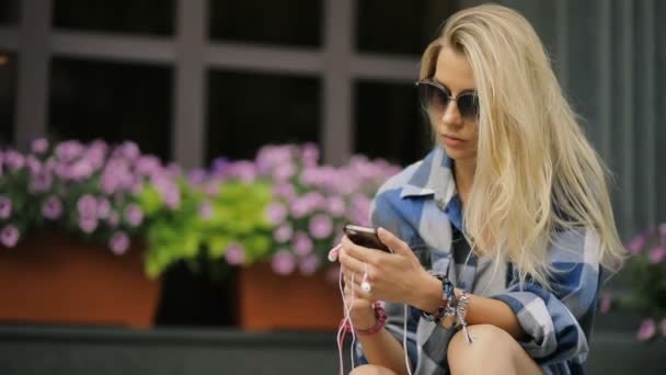 Жінка за допомогою смартфона сидить на міській вулиці — стокове відео