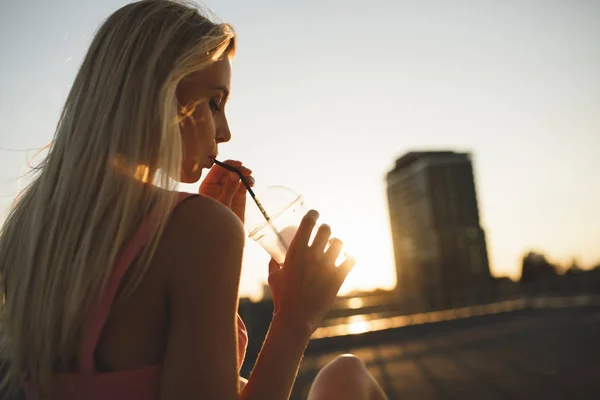 Frau trinkt Milchshake im Sonnenuntergang der Stadt — Stockfoto