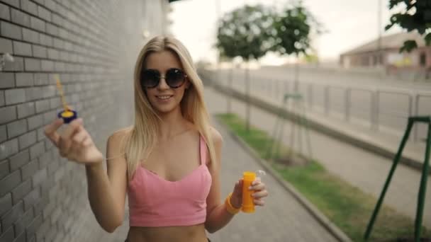 Красива жінка дме бульбашки на міській вулиці, повільний рух — стокове відео