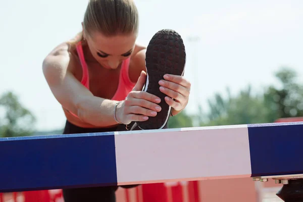 Joven atleta deportiva estira su pierna en el estadio — Foto de Stock