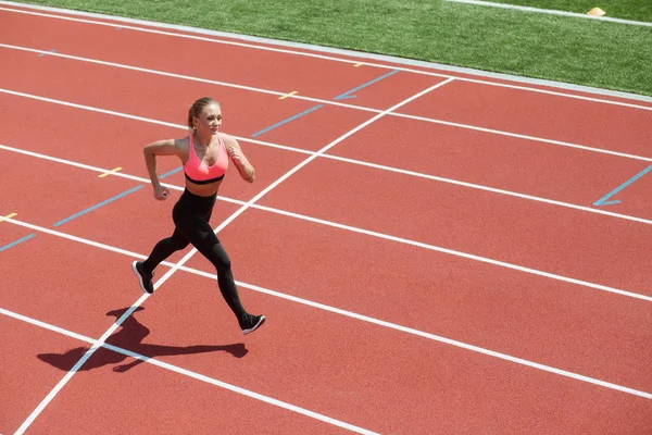 Deportiva joven atleta velocista corriendo en pista de estadio — Foto de Stock