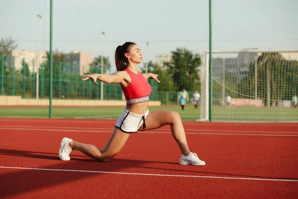 Giovane donna fitness carino. Attraente ragazza sportiva si allunga e si riscalda prima dell'allenamento nello stadio, concetto di stile di vita sano. Praticare posa yoga . — Foto Stock