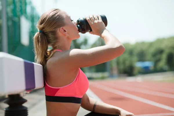 Genç sportif kadın atlet spor oturma, içme suyu veya protein shake Stadı, egzersiz kavramı üzerinden kokteyl