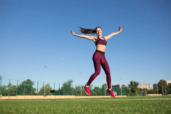 Atlama ve stadyum yeşil çimenlerin üzerinde açık havada uçan spor genç mutlu sporcumuz. O zevk yaz. Sağlıklı yaşam konsepti, spor aktivitesi. — Stok fotoğraf