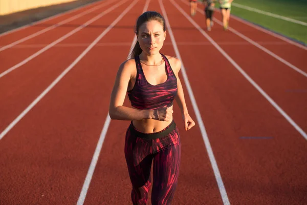 Deportista profesional atleta velocista corriendo en pista de estadio por la noche. Concepto de estilo de vida saludable. Adelante a la victoria . — Foto de Stock