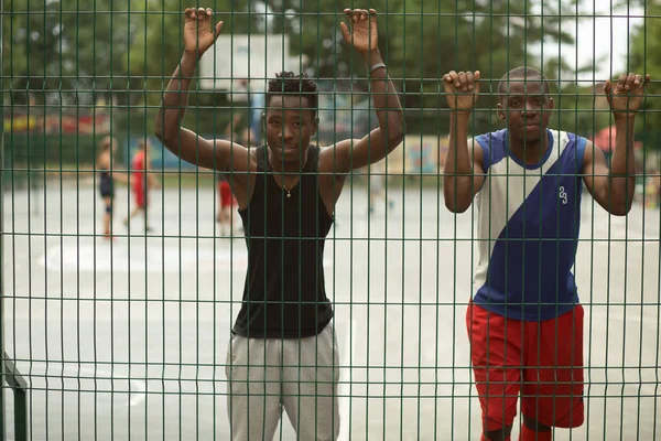 Två afrikanska amerikanska killkompisar som står vid staket av gatan basketplan — Stockfoto