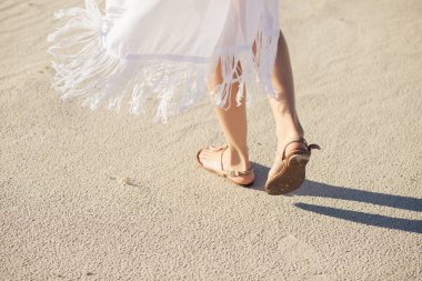 Sandaletler içinde kadın bacakları ıssız bir kumsalda git