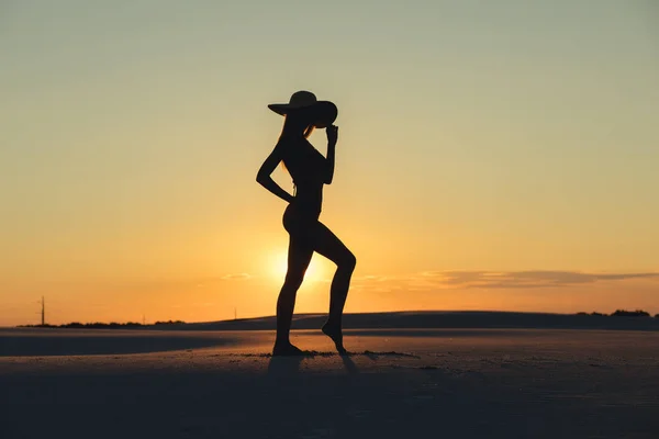 Silueta de hermosa mujer cuerpo posando en el desierto de oro al atardecer — Foto de Stock