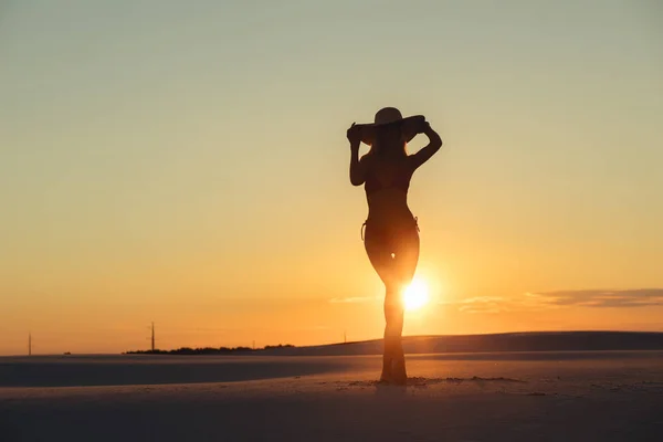 Silhouette de belle femme posant avec chapeau dans le désert d'or au coucher du soleil — Photo