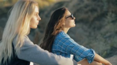 İki genç Gezgin kadın. Oturan ve gün batımında güneş gözlüğü takmış kız moda tarzı.