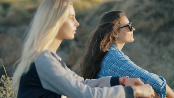 Dos jóvenes viajeras. Estilo de moda de las niñas sentadas y usando gafas de sol al atardecer . — Vídeo de stock