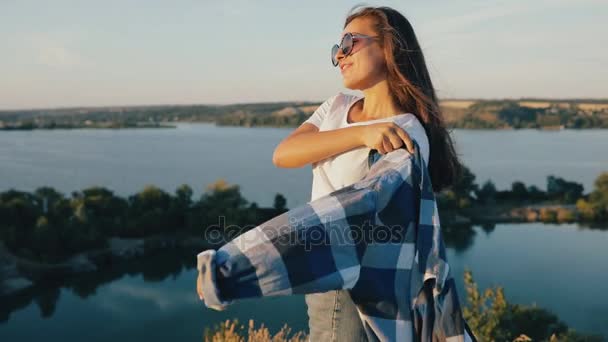 Schöne junge Frau auf Reisen. Mädchen, das allein wandert, genießt den Sommerurlaub bei Sonnenuntergang und steht mit erhobenen Händen — Stockvideo